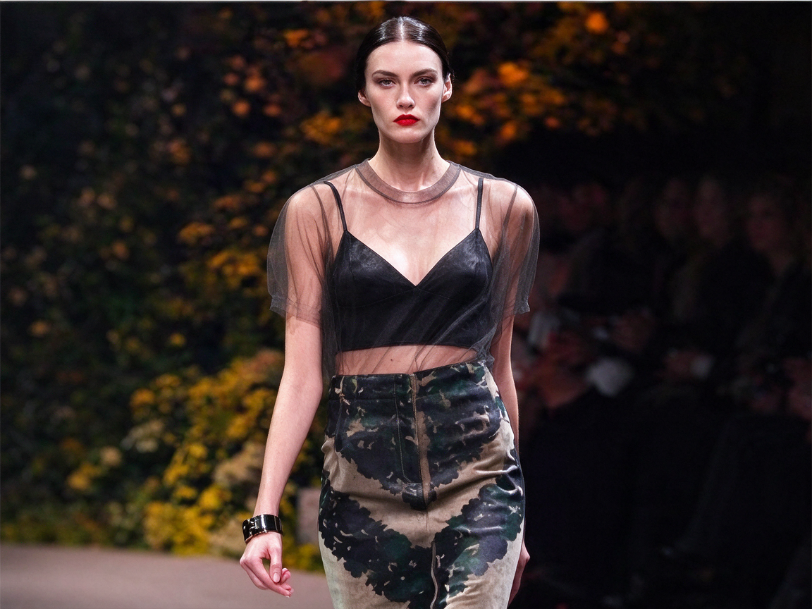 Woman styling a black triangle bralette beneath a sheer dark top with a patterned skirt outdoors